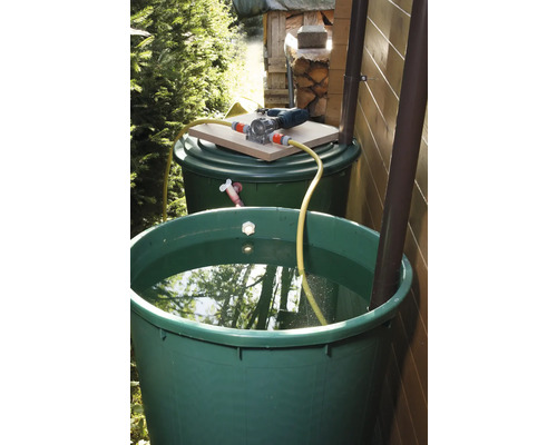 Zwei grüne Regentonnen mit Wasserpumpe und Schlauch im Garten.