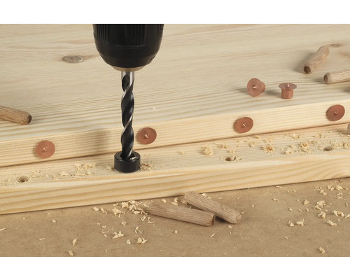 Bohrmaschine mit Dübelbohrer bohrt Loch in ein Holzbrett mit Markierungen