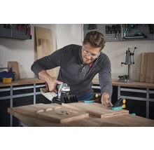 Mann benutzt eine Dübelfräse mit Holzverbindern und Werkstücken in einer Werkstatt.