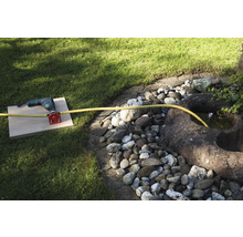 Eine Bohrmaschine mit Wasseranschluss und Schlauch im Garten.