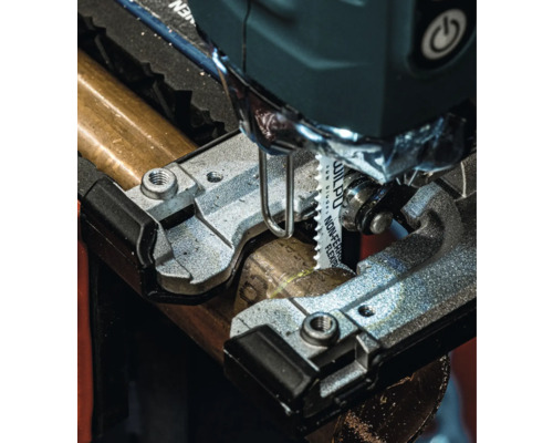 Nahaufnahme einer Stichsäge beim Schneiden eines Metallrohrs.