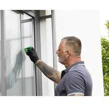 Eine Person verwendet einen Glasschaber, um eine Fensterscheibe zu reinigen.