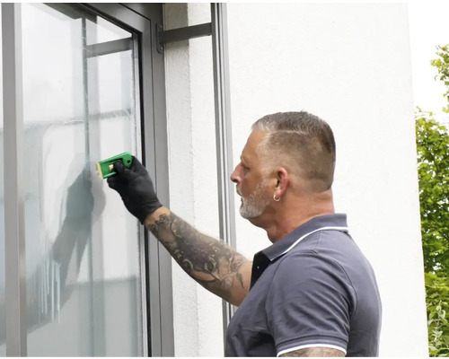 Eine Person verwendet einen Glasschaber, um eine Fensterscheibe zu reinigen.
