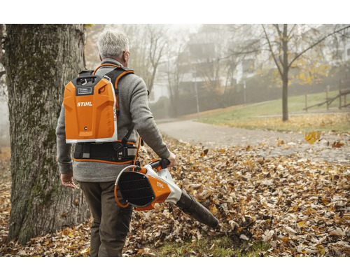 Mann benutzt einen tragbaren Laubbläser von Stihl im Garten.