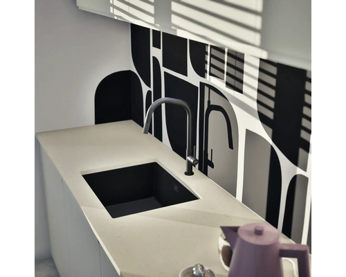 Küchenspüle mit Armatur auf einer Arbeitsplatte vor einer Wand mit grafischem Muster