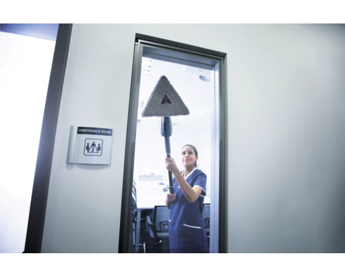 Reinigungskraft wischt Glasfläche mit dreieckigem Mopp