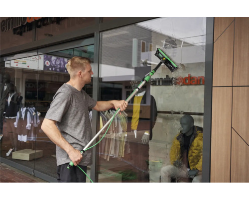 Ein Mann reinigt mit einem Fensterwischer ein Schaufenster.