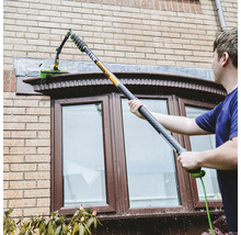 Fensterreinigung mit Teleskopstielbürste an einem Haus.