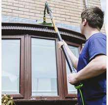 Mann reinigt Fenster mit Teleskop-Fensterwischer