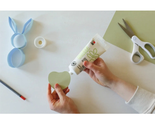 Bastelszene mit Klebstoff, Schere, Stift und Papier für ein Osterprojekt