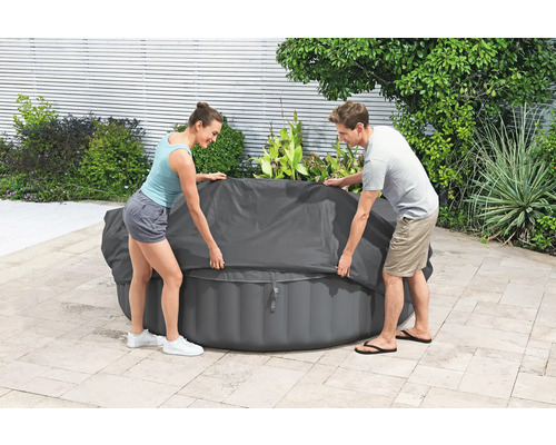 Aufblasbarer Whirlpool mit Abdeckung und zwei Personen im Garten.