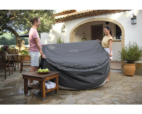 Personen legen eine Abdeckung über einen Whirlpool im Garten.