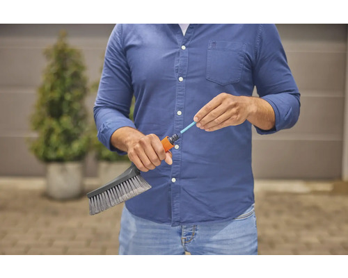 Eine Person schließt eine Bürste an einen Gartenschlauch an