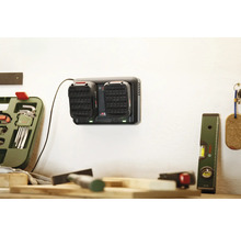 Akkuladegerät mit zwei Akkus an einer Wand in einer Werkstatt.