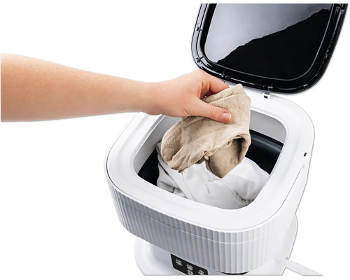 Wäsche wird in eine tragbare Waschmaschine gegeben.