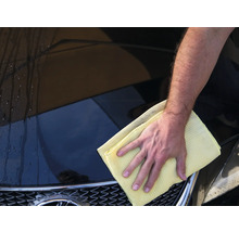 Ein Mann wischt ein Auto mit einem Tuch.