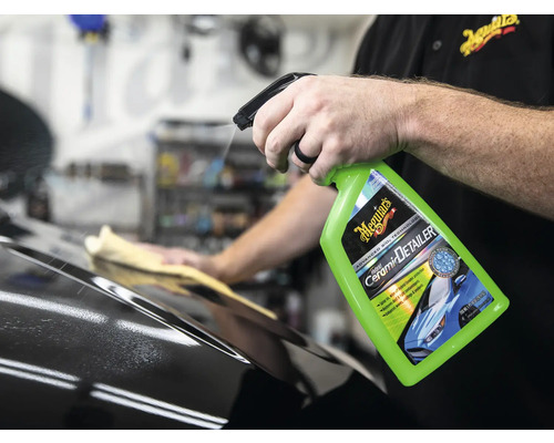 Detailer wird auf ein Auto gesprüht, im Hintergrund wischt eine Person die Oberfläche mit einem Tuch ab. Meguiars Logo.