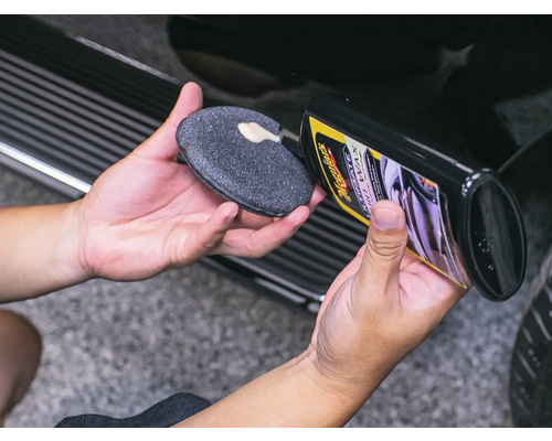 Person trägt Autopolitur auf einen Applikator auf