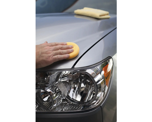 Autopflege: Eine Person poliert ein Auto mit einem Schwamm.