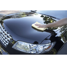 Eine Person reinigt ein Auto mit einem Tuch.