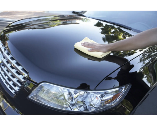 Eine Person reinigt ein Auto mit einem Tuch.