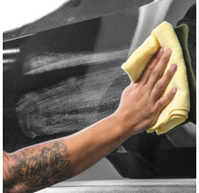 Reinigung eines schwarzen Autos mit einem Tuch.