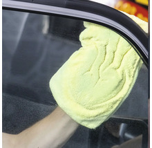 Eine Person reinigt eine Autoscheibe mit einem gelben Tuch.