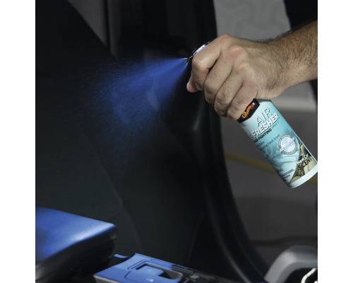 Eine Hand sprüht Lufterfrischer in das Innere eines Autos.