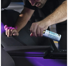 Person sprüht Geruchsneutralisierer in ein Auto.