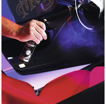 Eine Person sprüht Lufterfrischer in das Innere eines Autos.