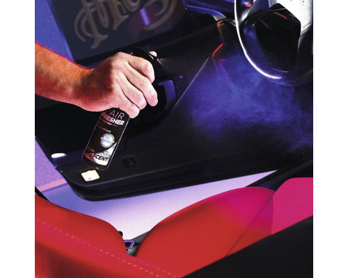 Eine Person sprüht Lufterfrischer in das Innere eines Autos.