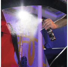 Ein Mann sprüht Lufterfrischer in ein Auto, um Gerüche zu bekämpfen.