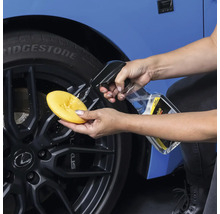 Autopflege: Person reinigt Felge mit Schwamm und Reiniger