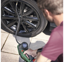 Eine Person pumpt einen Autoreifen mit einem tragbaren Reifenfüller auf