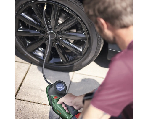 Eine Person pumpt einen Autoreifen mit einem tragbaren Reifenfüller auf