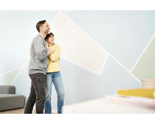 Paar betrachtet geometrische Wandgestaltung im Wohnzimmer.