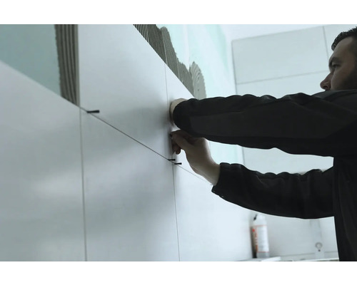 Fliesenleger bei der Arbeit mit Fliesen und Fliesenschnüren