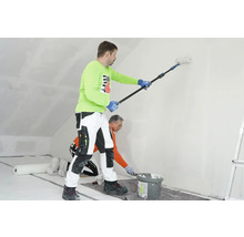 Zwei Handwerker renovieren einen Raum mit Farbroller und Spachtel