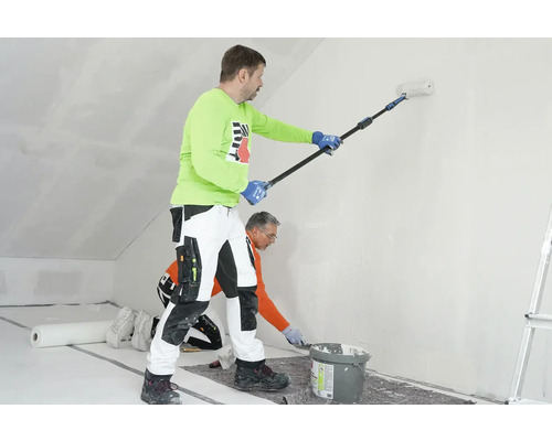 Zwei Handwerker renovieren einen Raum mit Farbroller und Spachtel