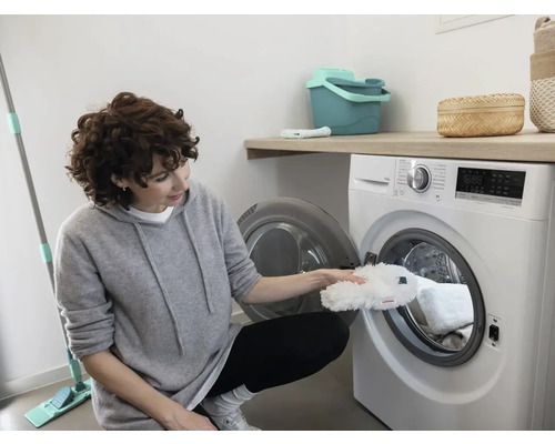 Frau legt einen Moppbezug in eine Waschmaschine