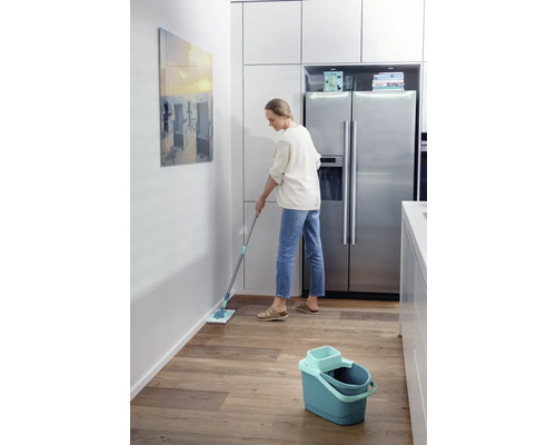 Frau wischt Fußboden mit einem Mopp in einer Küche.