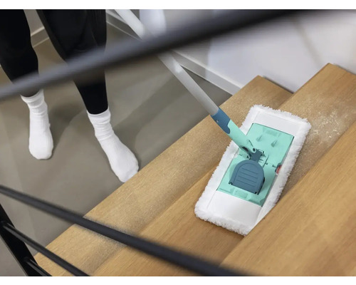 Eine Person reinigt eine Holztreppe mit einem Bodenwischer.