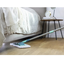 Szene eines Zimmers mit Bett, Nachttisch und Wischmopp auf einem Holzboden.