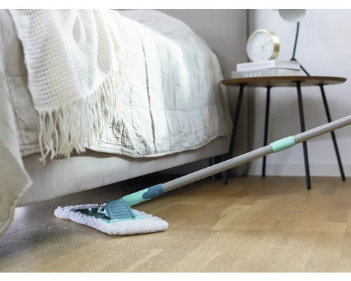 Szene eines Zimmers mit Bett, Nachttisch und Wischmopp auf einem Holzboden.