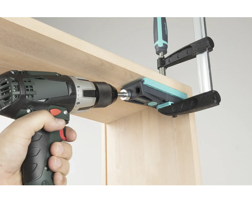 Akkuschrauber beim Bohren durch eine Bohrlehre in ein Holzbrett