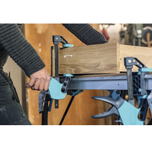 Eine Werkbank mit einer Schraubzwinge fixiert ein Holzstück.