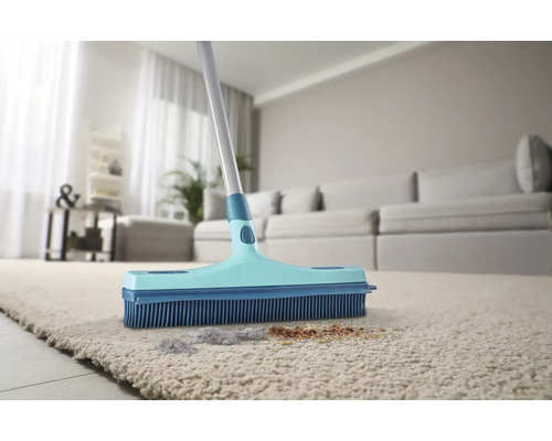 Bürste mit Gummiborsten auf einem Teppich mit Schmutz