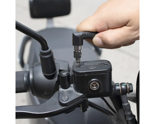 Eine Person verwendet einen Schraubendreher mit Winkelvorsatz, um an einem Motorrad zu arbeiten.