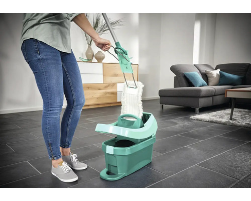 Frau benutzt Mopp mit Eimer im Wohnzimmer für die Bodenreinigung