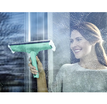 Frau reinigt Fenster mit einem Fensterwischer